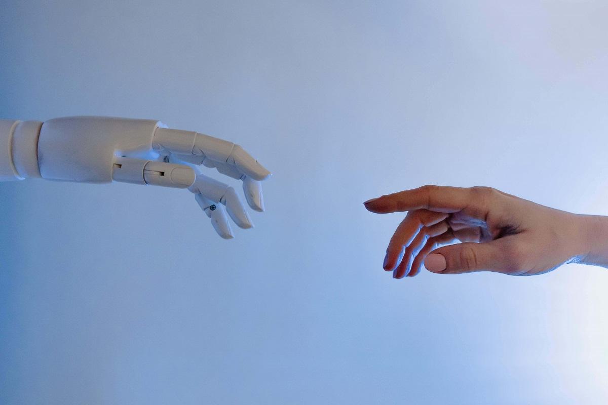 Foto de duas mãos, uma humana e outra de inteligência artificial