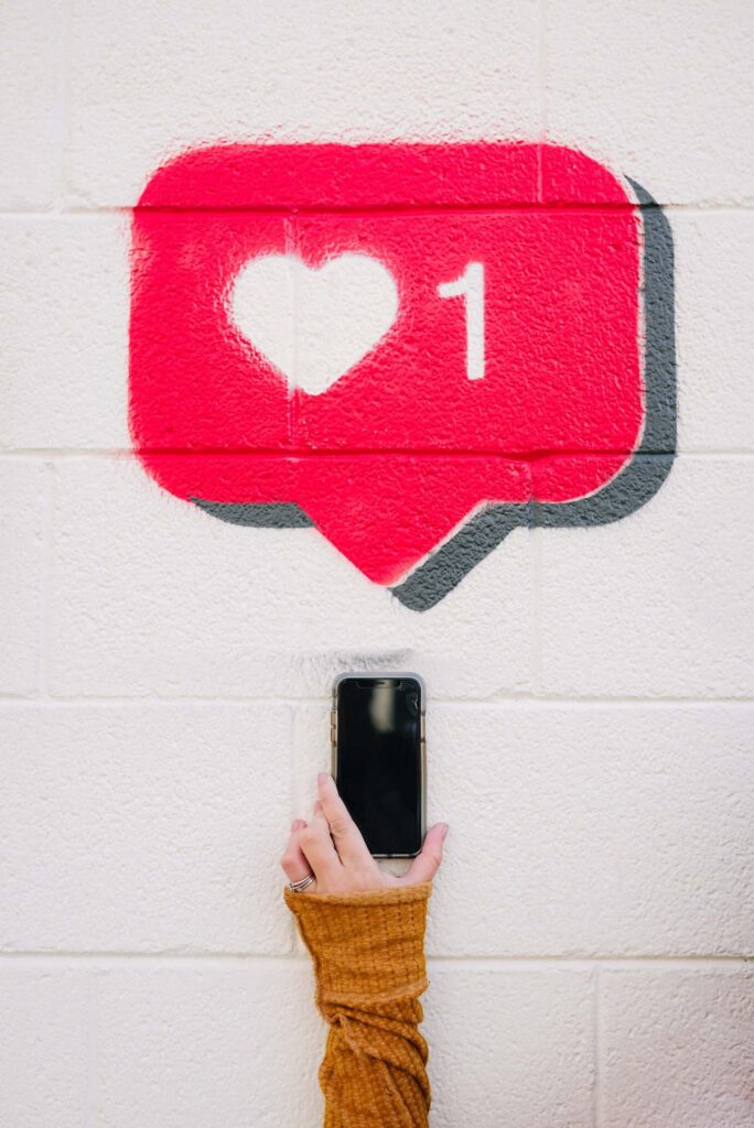 Mão segurando celular apontado para graffiti de balão de notificação, como criar conteúdo para o instagram.