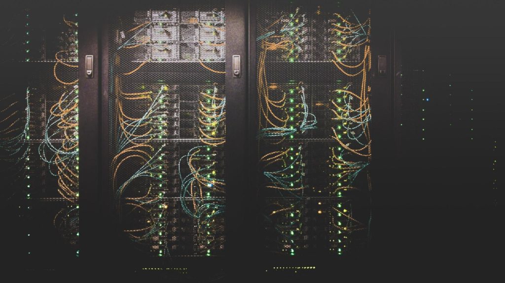 Centro de dados com máquinas de onde saem fios coloridos.