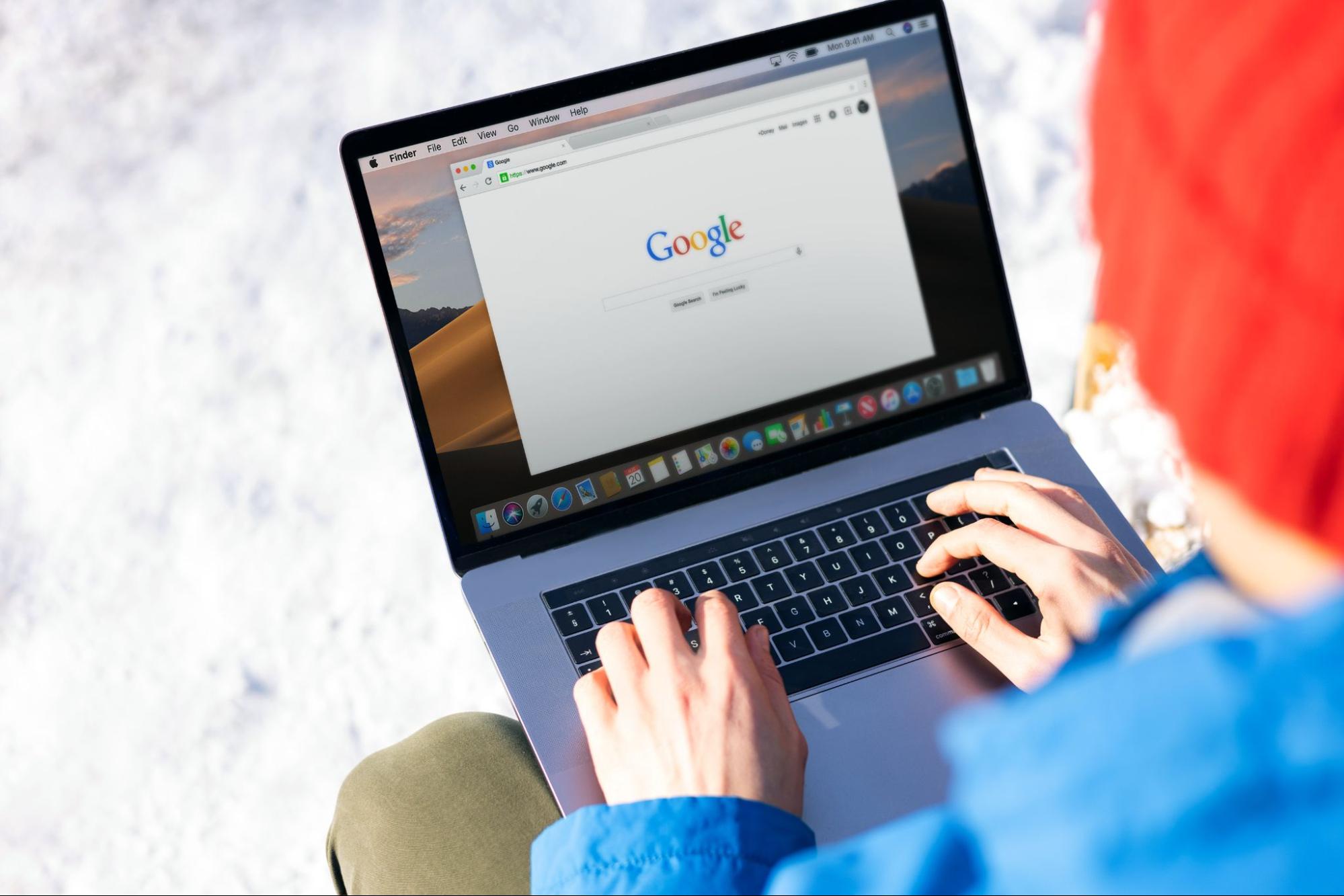 Pessoa de cabelo vermelho e blusa azul acessando o google pelo computador.