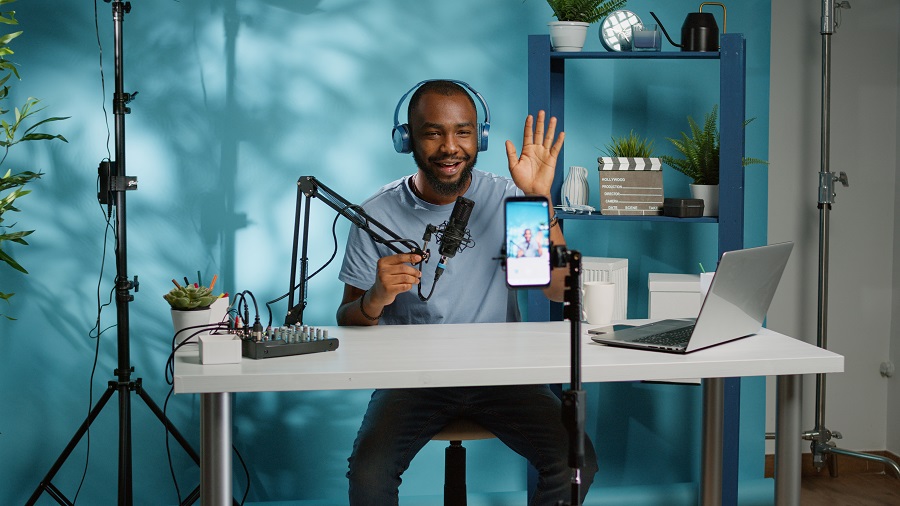 Homem negro vlogger utilizando um smartphone para gravar seu podcast no estúdio