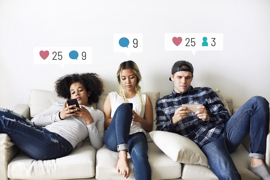 Jovens adultos sentados no sofá usando seus respectivos smartphones