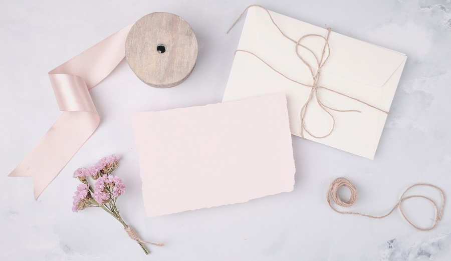 Itens de papelaria em tons variados de rosa: papéis, fitas e flores