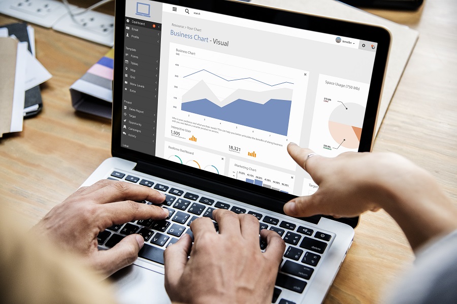 Pessoas trabalhando em um único notebook analisando um relatório provavelmente de Power BI.