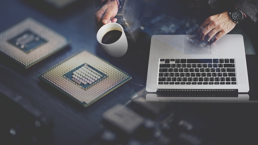 Homem usando um notebook e segurando uma caneca de café.