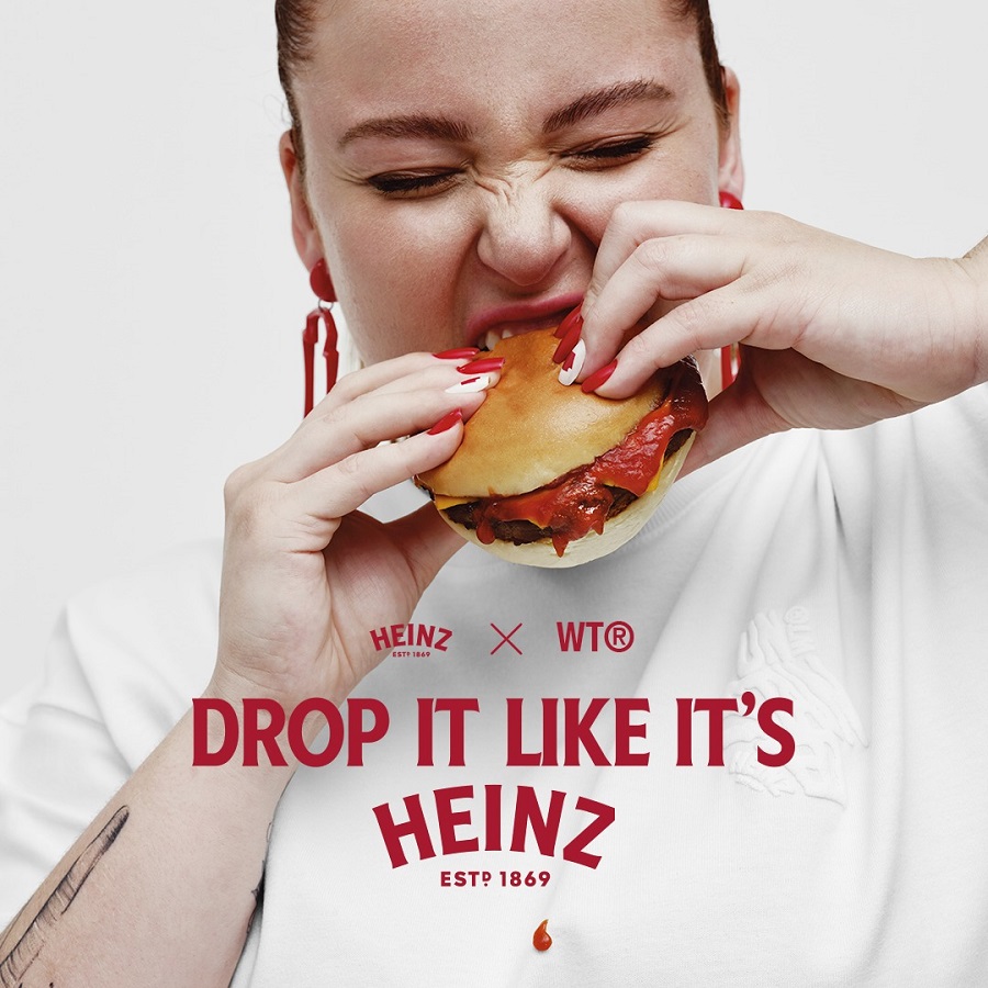 Mulher comendo hambúrguer. Em texto, está escrito "Drop it like it's Heinz".