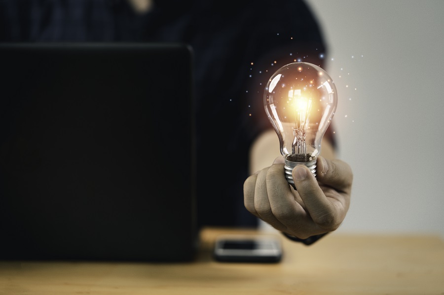 Mão de empresário segurando lâmpada com luz brilhante para pensamento criativo