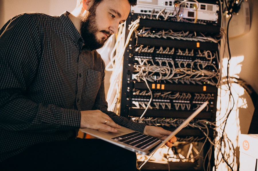 homem mexendo em computador conectado a um servidor