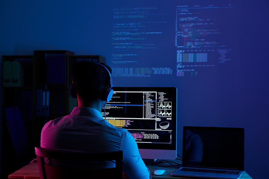 homem em frente ao computador com códigos na tela