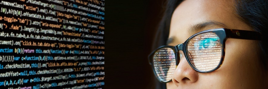 olhos de uma mulher de óculos observando uma tela com códigos