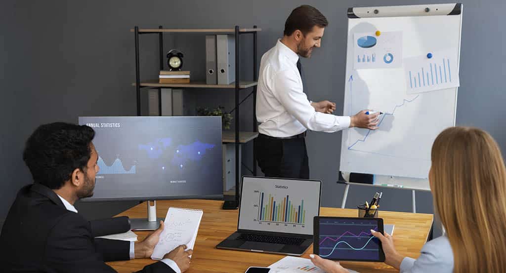 Três profissionais discutindo relatórios, dados e estatísticas, exemplificando na prática o que é business intelligence e para que serve em uma empresa.