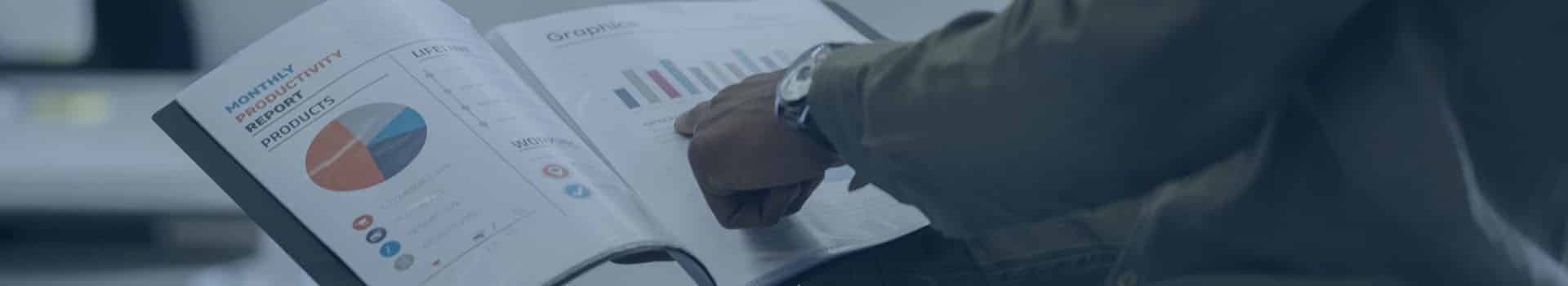 Pessoa analisando exemplos de dashboard do Power BI em uma pasta, com gráficos e indicadores financeiros exibidos nas folhas.