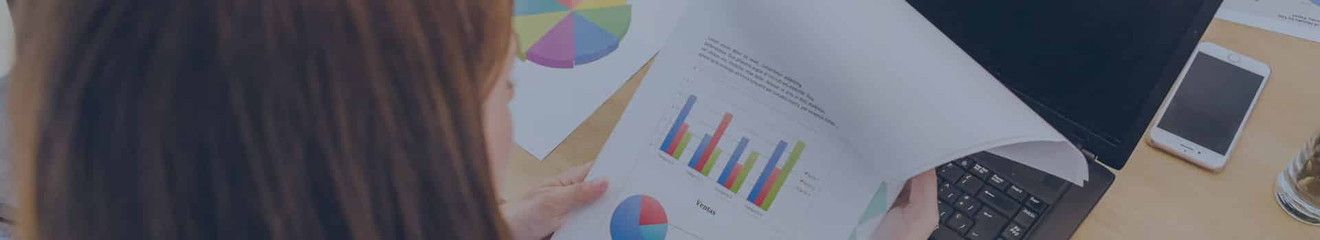 Estudante analisando gráficos e relatórios impressos, ilustrando como são os estudos nos melhores cursos de BI.