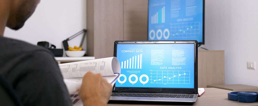 Profissional analisando gráficos e lendo material de estudo para aprender BI e aprimorar suas habilidades em análise de dados.