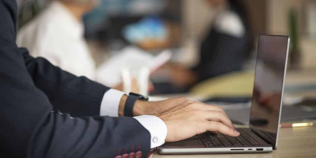Profissional digitando em um laptop em ambiente corporativo, focado em estratégias sobre como aprender BI e análise de dados.