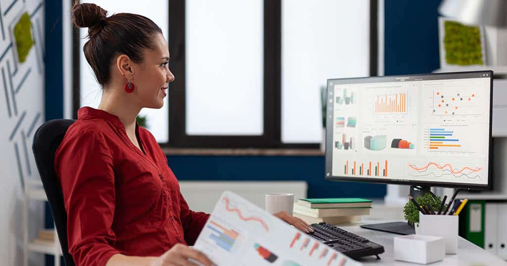Profissional mulher analisando relatórios e gráficos para entender o que faz Business Analytics e sua aplicação estratégica.