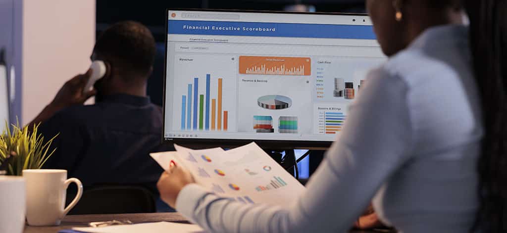 Profissional analisando dados e gráficos na tela do computador, representando como é atuar na área de BI e o uso de Business Intelligence para tomada de decisões.