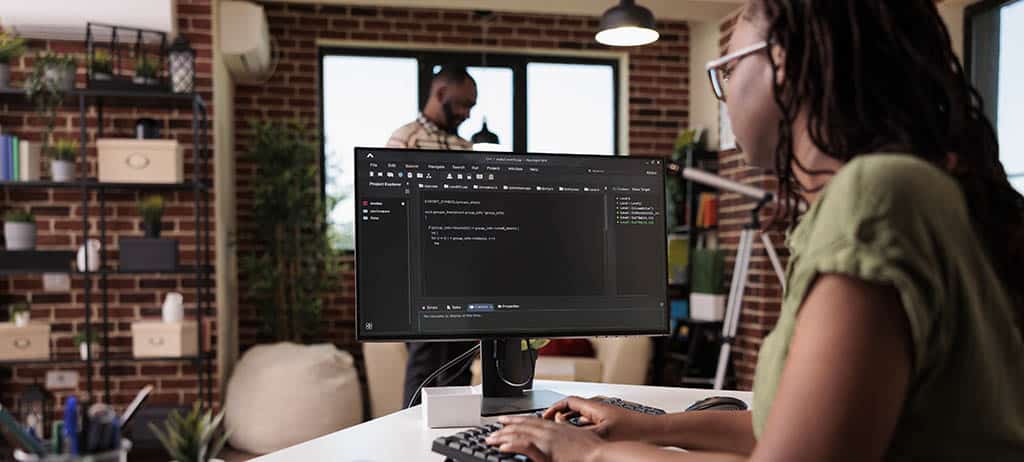 Desenvolvedora trabalhando em desenvolvimento back end em um ambiente moderno, escrevendo código em um monitor.