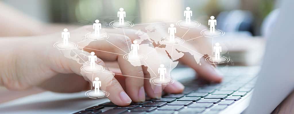 Mãos digitando em um laptop com um mapa digital e conexões globais, representando o que é redes e sua importância na conectividade mundial.