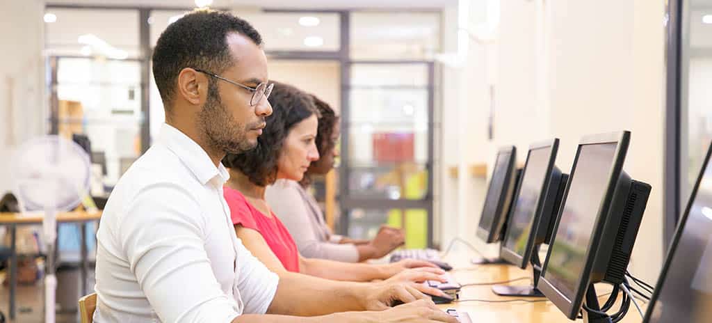 Grupo de pessoas utilizando computadores em rede, ilustrando a importância das redes de computadores na conectividade e colaboração digital.