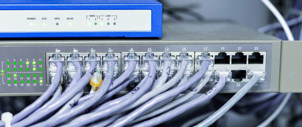 Switch de rede com múltiplos cabos conectados, exemplificando diferentes tipos de redes de computadores e sua infraestrutura.