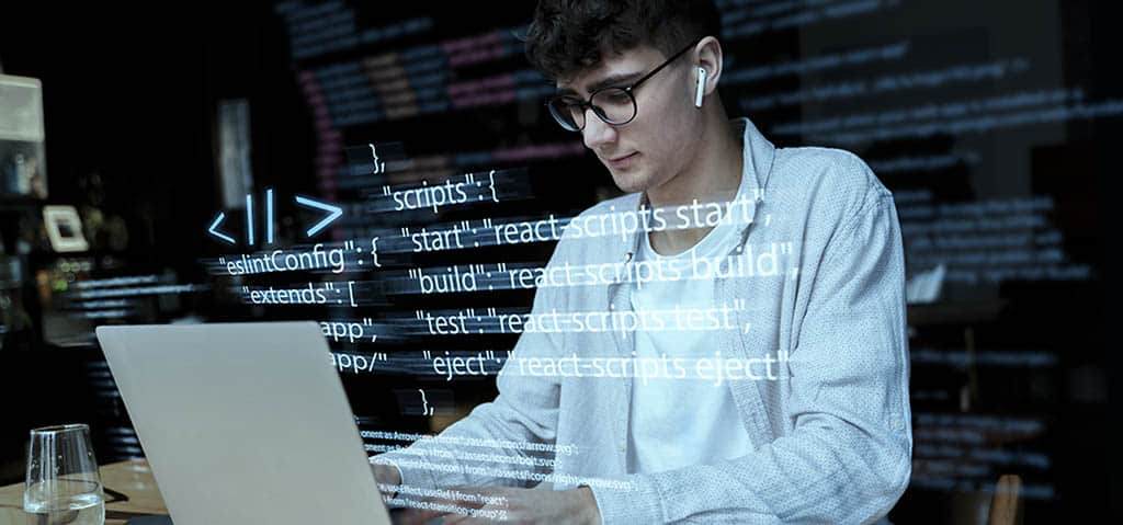 Desenvolvedor programando em laptop com código flutuante na tela, representando virtualização e ambientes computacionais isolados para desenvolvimento.