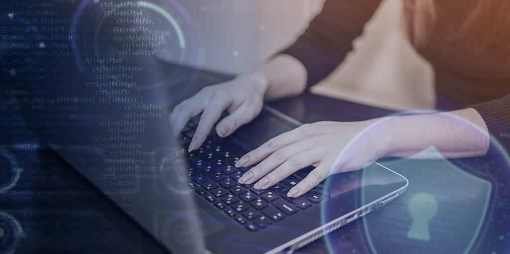 Mãos femininas digitando em um laptop com códigos e ícones digitais enquanto trabalha seguindo os princípios e as boas práticas da arquitetura de software.