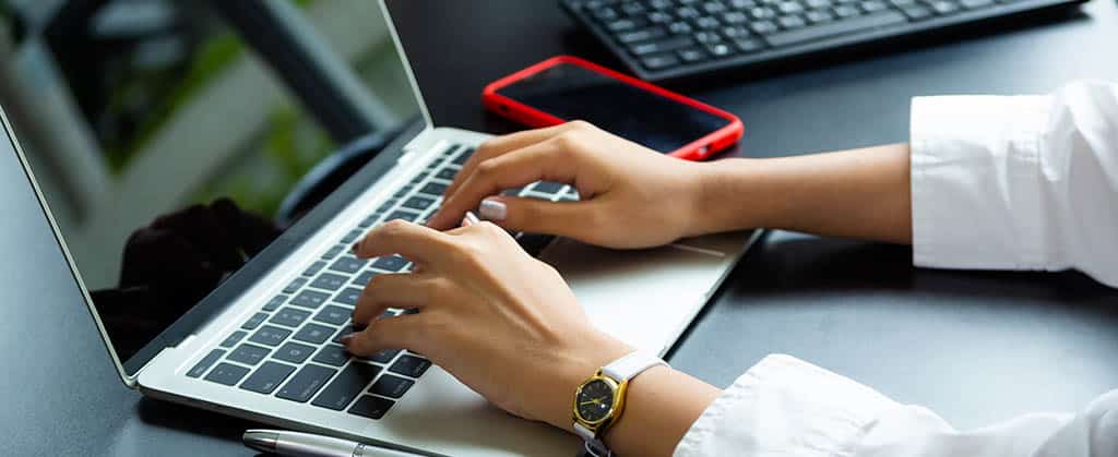 Pessoa digitando em laptop, representando programação de back-end PHP.