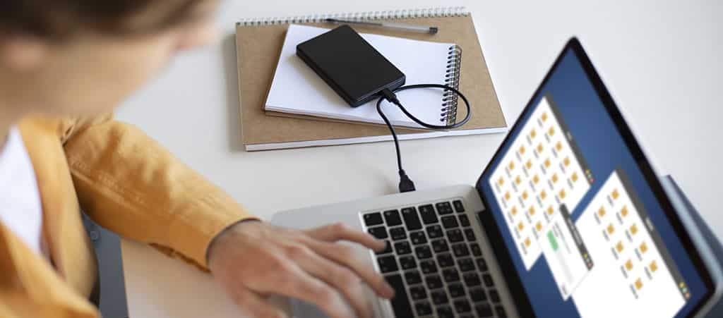 Pessoa utilizando um laptop para gerenciar arquivos, representando a prática e aprendizado em um curso de redes.