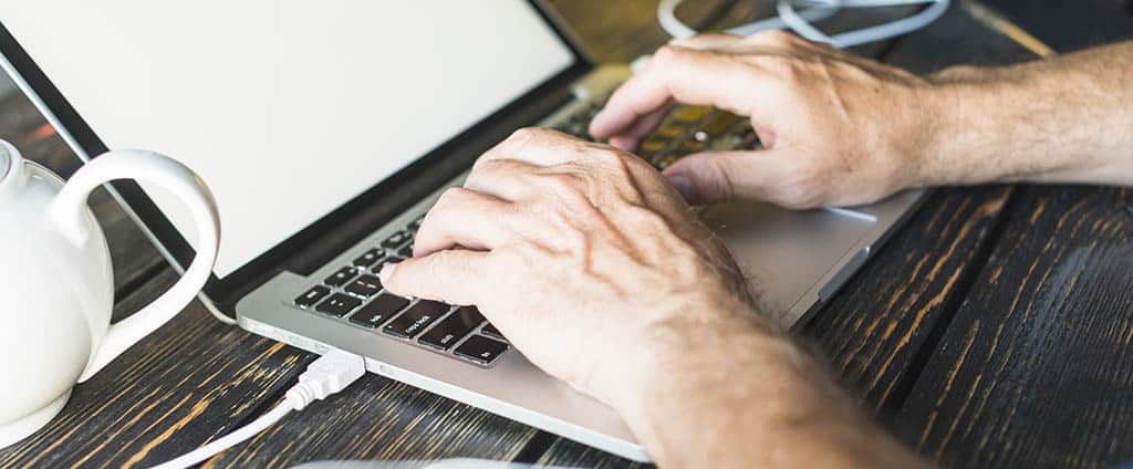 Profissional digitando no laptop enquanto estuda para seu mestrado em redes de computadores.