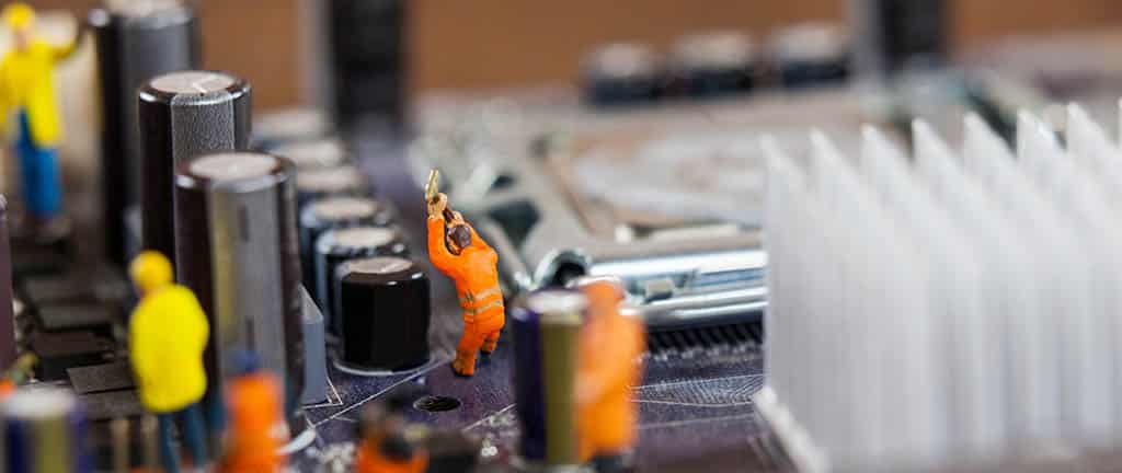 Miniaturas simulam o trabalho de um engenheiro de redes em uma placa-mãe, representando a manutenção e otimização de sistemas.