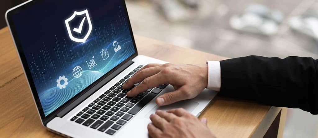 Pessoa utilizando um laptop com ícones de segurança digital, representando os benefícios do uso de máquinas virtuais online para proteção e otimização de sistemas.