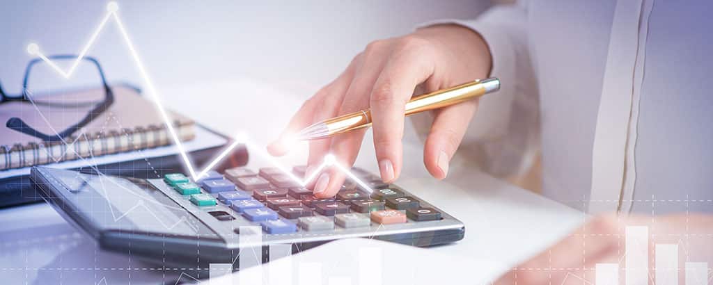 Pessoa usando uma calculadora com gráficos financeiros, representando a análise de quanto ganha um desenvolvedor mobile no mercado de tecnologia.