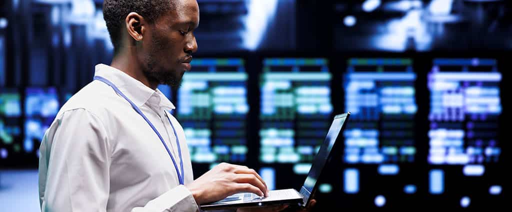 Profissional de TI usando o InterMapper para monitoramento de redes em um data center, analisando servidores e tráfego de rede em tempo real.