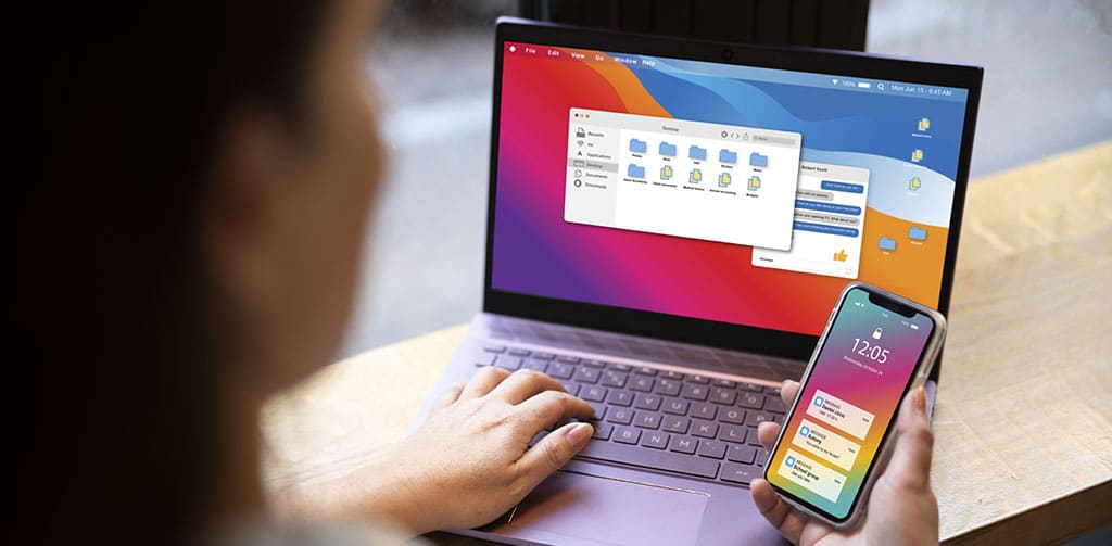 Usuária gerenciando um app no celular enquanto trabalha em um laptop, ilustrando o uso de uma plataforma no code gratuita para desenvolvimento de aplicativos.
