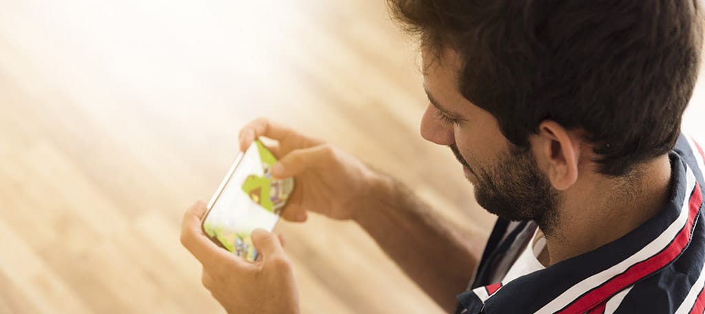 Homem jogando no celular, explorando recursos sobre como fazer um jogo no celular.
