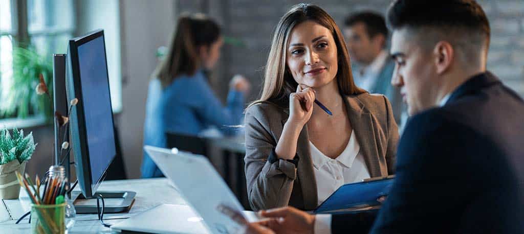 Um homem e uma mulher em ambiente de trabalho discutindo a melhor grafia, se backend ou back-end.