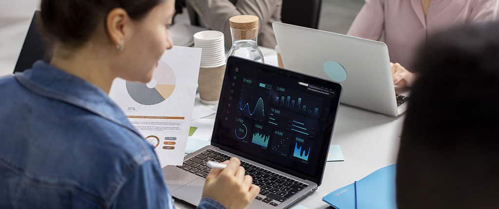Equipe analisando dados em dashboard digital, demonstrando o uso do AirWave para monitoramento e gestão de redes corporativas.