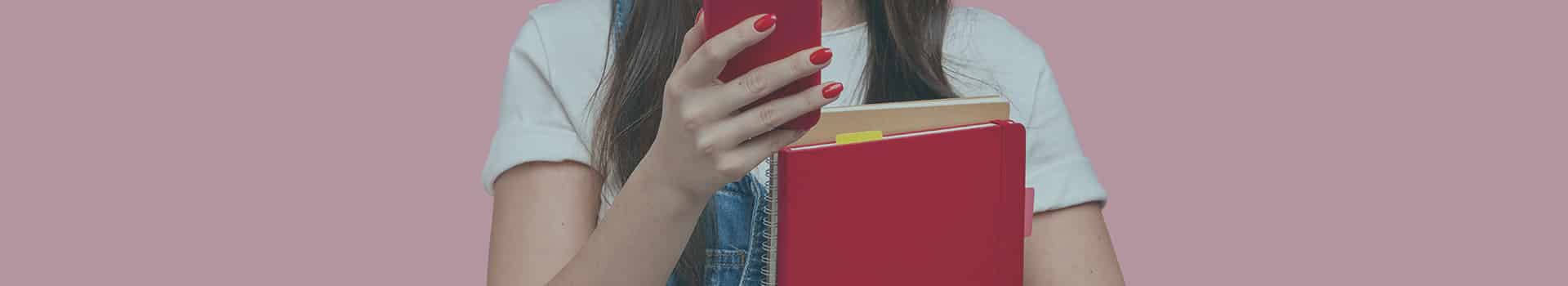 Mulher segurando um celular e um livro desenvolvimento Android, representando estudo e tecnologia.
