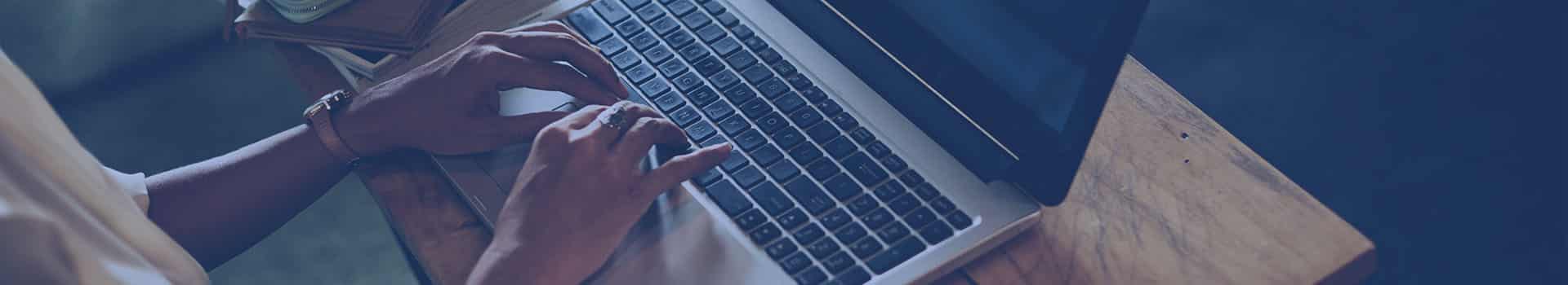 Pessoa trabalhando em um laptop em um ambiente aconchegante, possivelmente utilizando o WhatsUp Gold para monitoramento de rede.