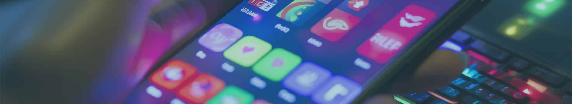 Mão segurando smartphone com aplicativos iluminados, representando o desenvolvimento de tecnologia móvel e inovação digital na plataforma android.