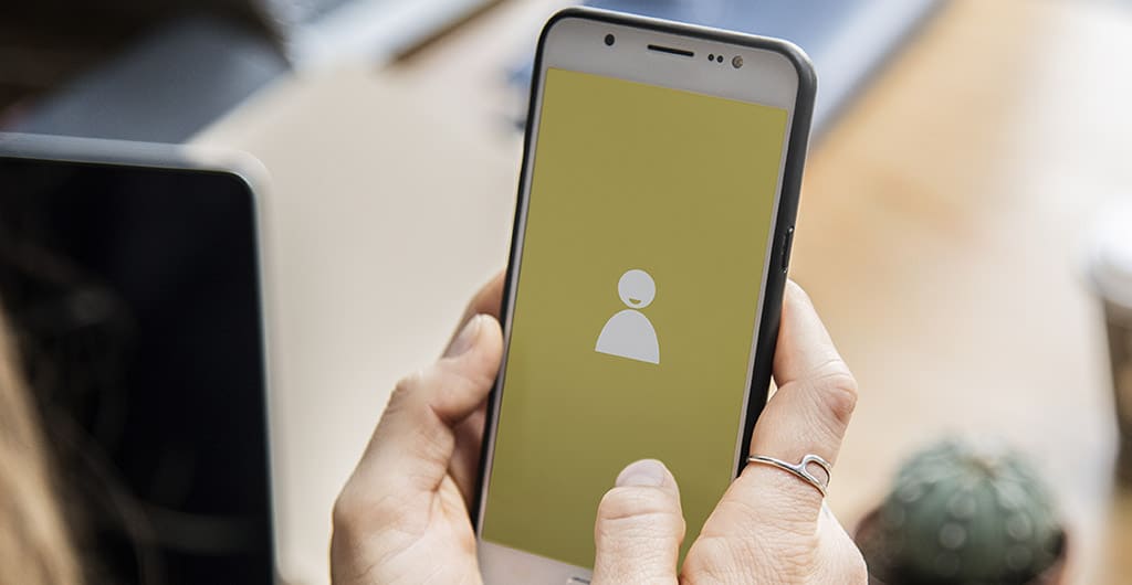 Pessoa segurando um smartphone com tela de login, representando o acesso à Play Store como desenvolvedor para gerenciar aplicativos.