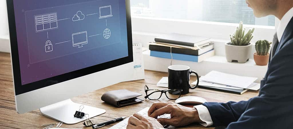 Profissional gerenciando infraestrutura de NFV em um computador, representando a virtualização das funções de rede na nuvem.