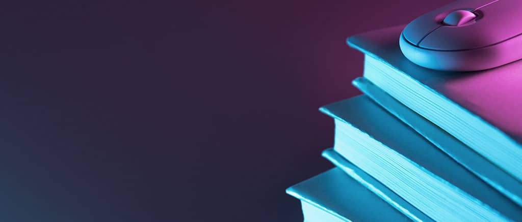 Livros de arquitetura de software empilhados sobre um teclado, representando os melhores livros para aprender sobre desenvolvimento de sistemas.
