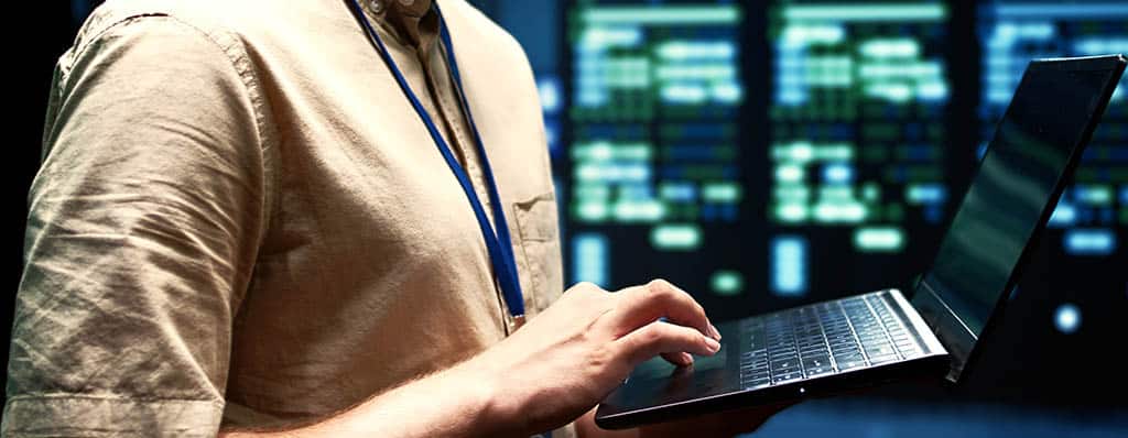 Técnico de TI monitorando servidores com um laptop, ilustrando a gestão de infraestrutura de rede com o OpManager.