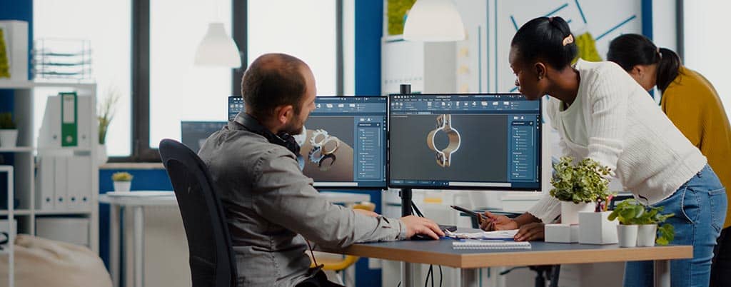 Equipe de engenheiros analisando modelos em CAD, representando a arquitetura de projeto de software para design e desenvolvimento de sistemas.