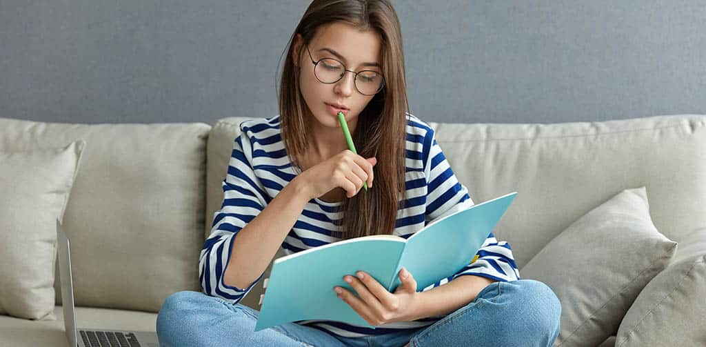 Jovem estudando com laptop e anotações, se preparando para ingressar na carreira e entender o salario de arquiteto de software.