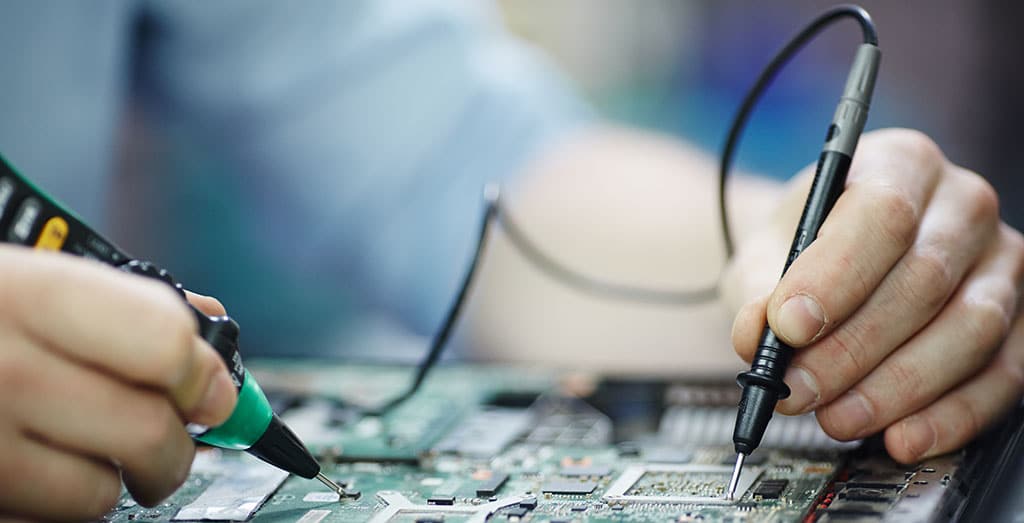 Técnico analisando circuito de um laptop, representando a arquitetura de hardware e a estrutura física dos componentes eletrônicos.