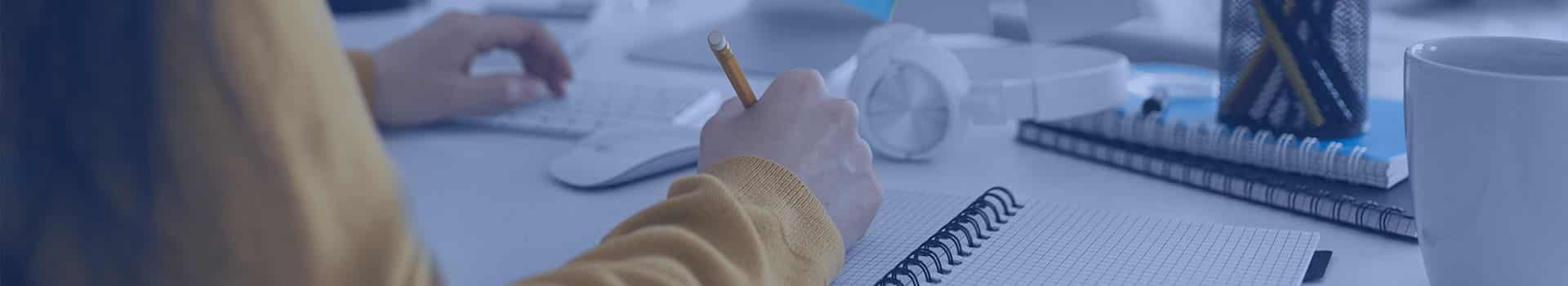 Pessoa estudando um curso VMware em um laptop, com anotações ao lado.