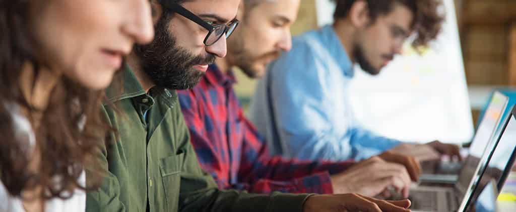 Grupo de profissionais utilizando laptops, representando pessoas participando de um curso de virtualização.